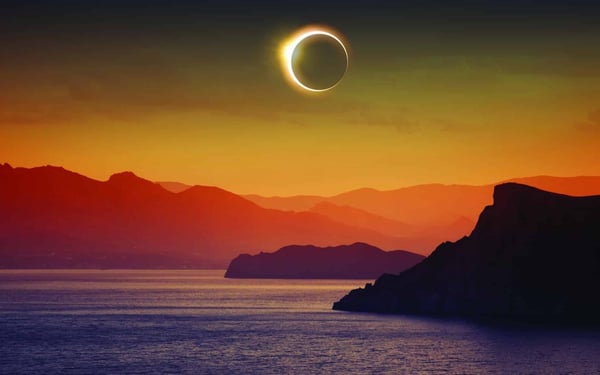 Full solar eclipse over mountains and sea