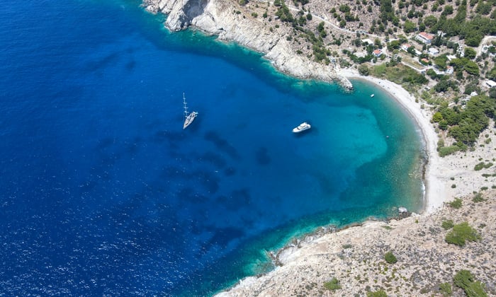 Beach and yachts on Icaria, one of the best quiet Greek islands to cruise to
