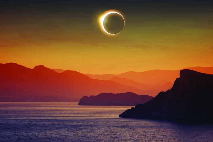 Full solar eclipse over mountains and sea